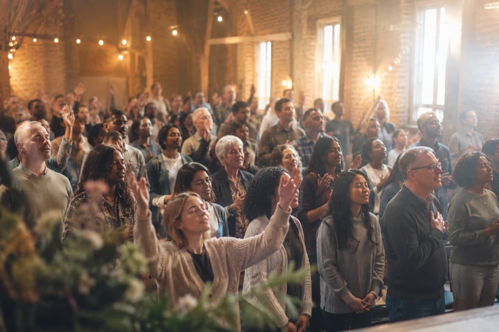 A congregation worshipping together on a Sunday morning, hands raised in a warmly lit church